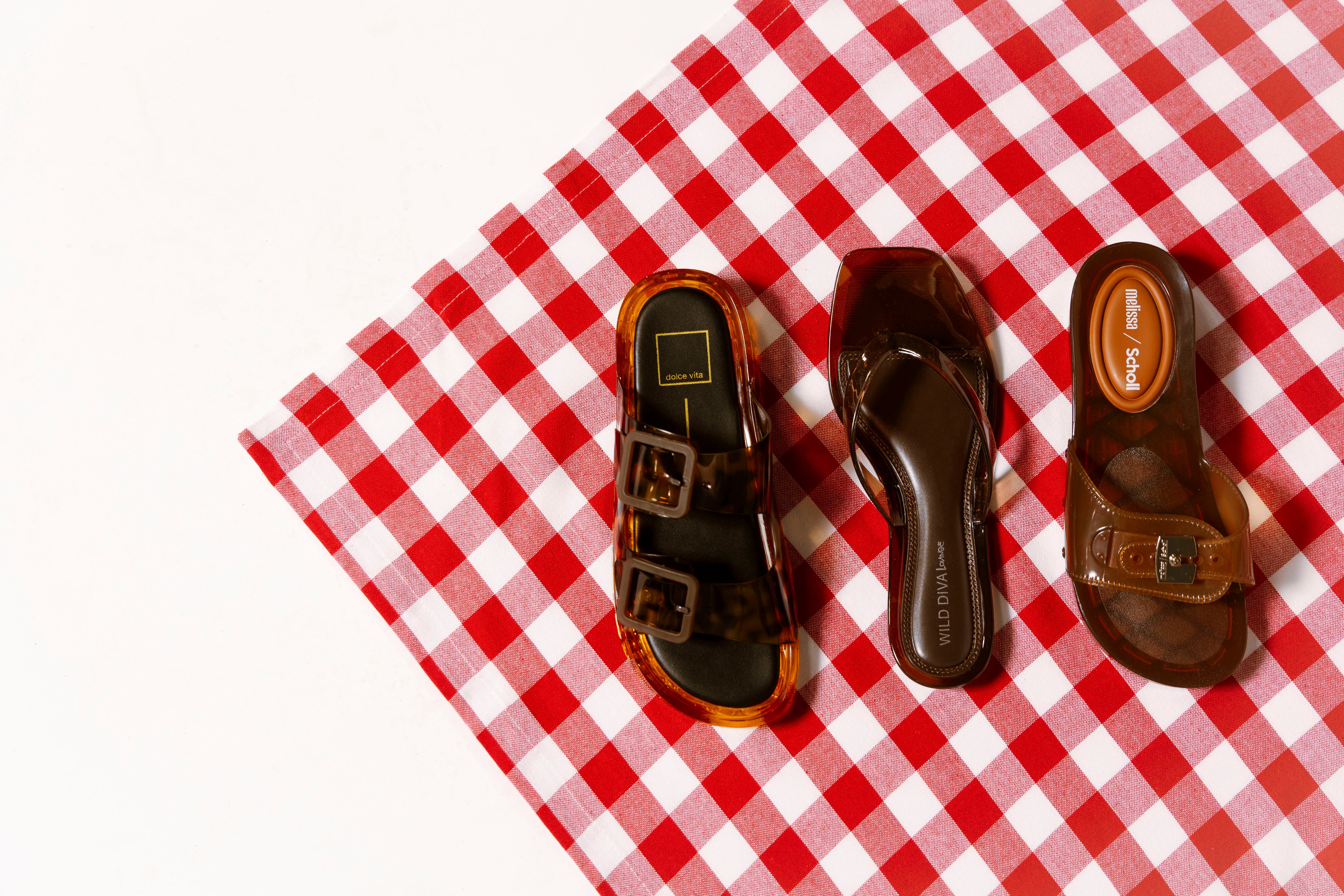 a picture of three brown jelly sandals on red gingham cloth. link to shop new arrivals for 20% off sale